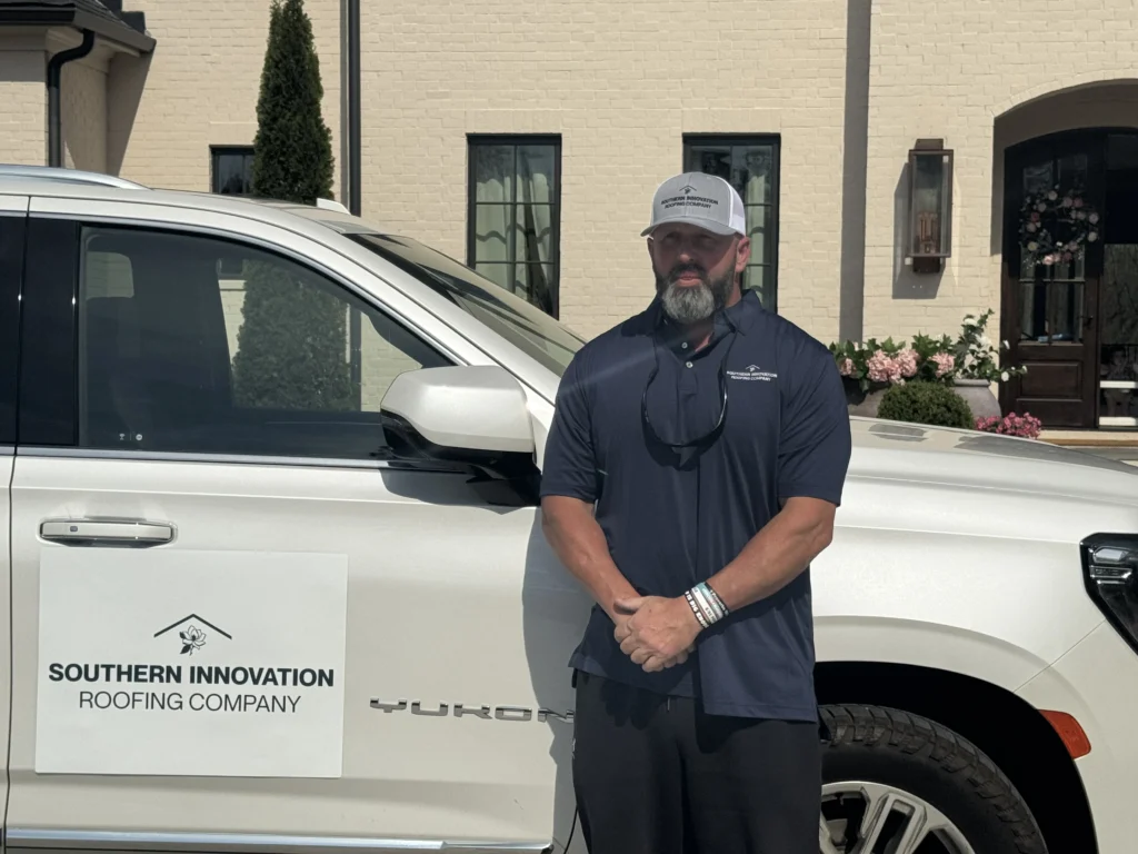 Brandon standing in front of a branded roofing company truck