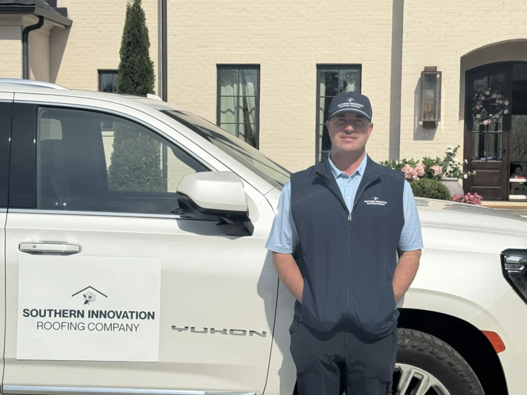 Lance standing with a branded roofing company truck representing operations leadership